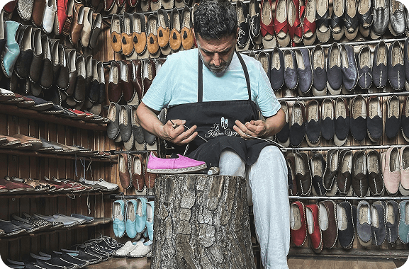 A cobbler uses a digital platform to manage and fulfill customer shoe repair and design orders, ensuring timely service.