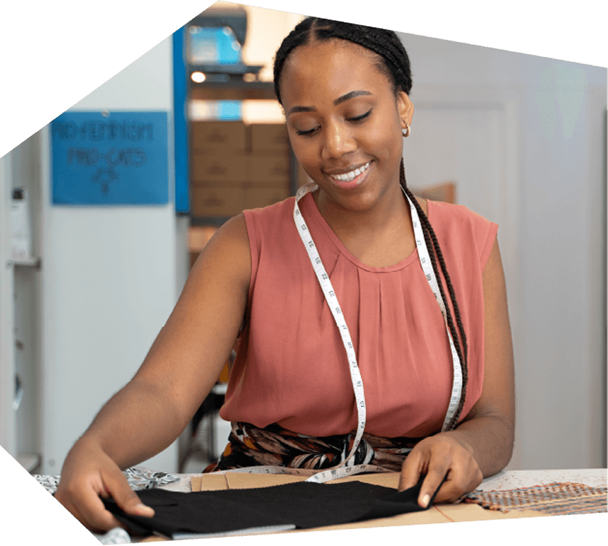 Fashion Designer Measuring Fabric in Studio A happy fashion designer carefully measures fabric in her studio, preparing for a new project.